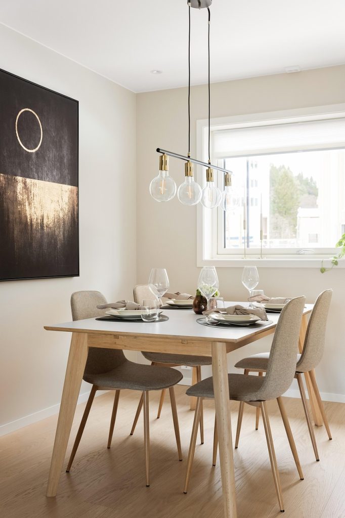 Salle à manger moderne avec mobilier scandinave et éclairage design Salle à manger épurée avec table en bois clair, chaises beiges et suspension lumineuse contemporaine
