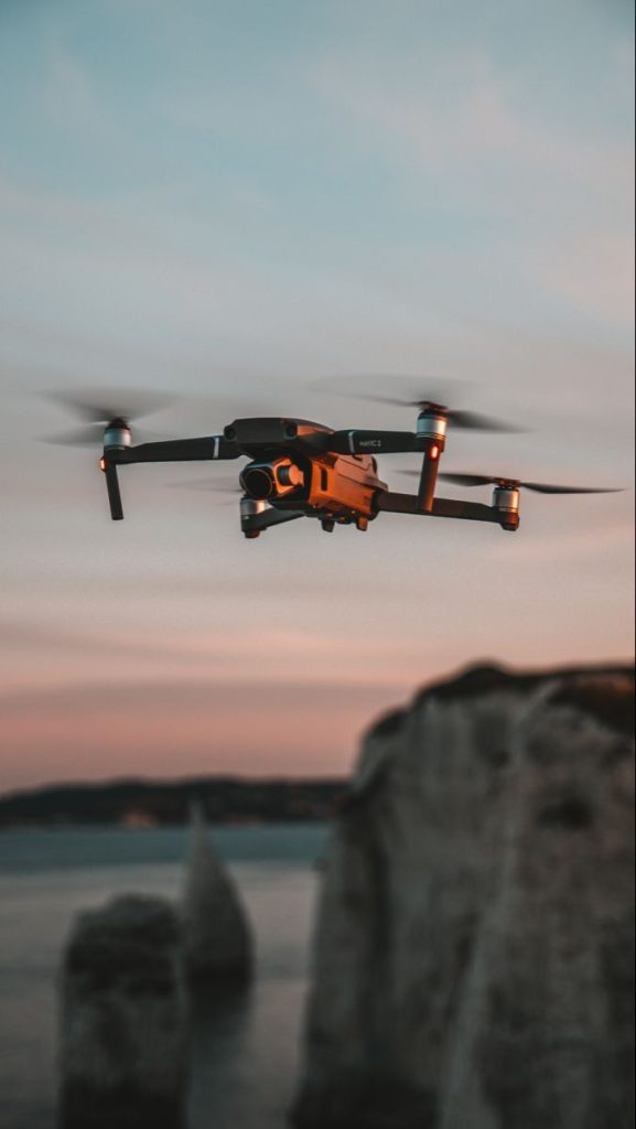 Drone en vol au-dessus des falaises au coucher du soleil Drone volant au-dessus de formations rocheuses en bord de mer au crépuscule